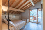 This stunning bedroom boasts a unique architectural design with exposed wooden beams and a high ceiling, creating a warm and inviting atmosphere.
