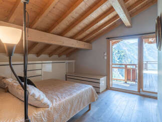 This stunning bedroom boasts a unique architectural design with exposed wooden beams and a high ceiling, creating a warm and inviting atmosphere.