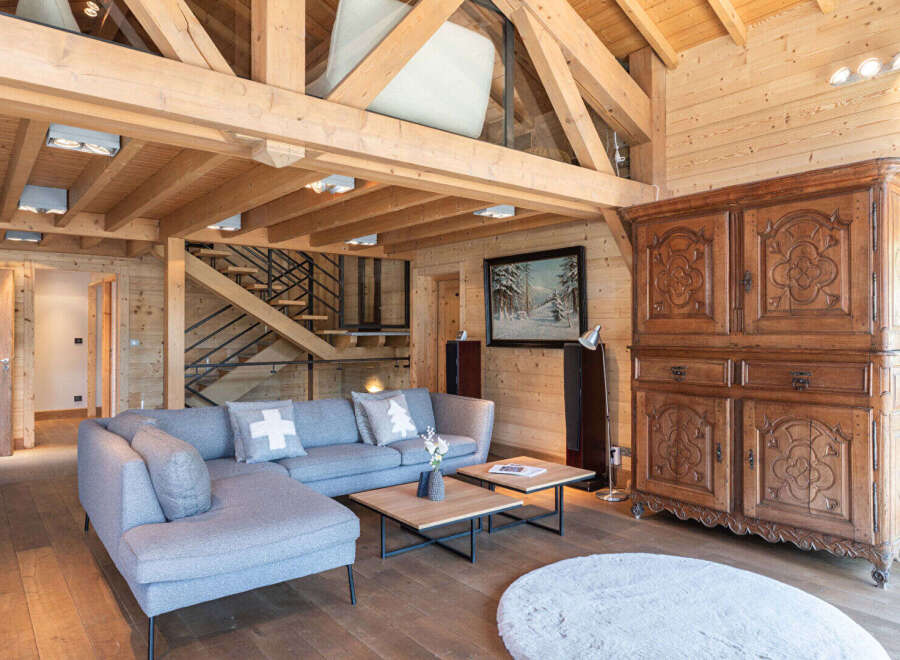 Experience the charm of this stunning property, featuring a cozy living space with a modern gray sofa and a unique wooden ceiling.