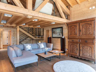 Experience the charm of this stunning property, featuring a cozy living space with a modern gray sofa and a unique wooden ceiling.