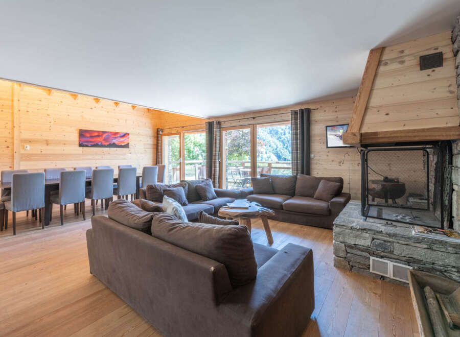 Experience luxury living in this stunning chalet, featuring a spacious living area with a cozy fireplace and comfortable seating.