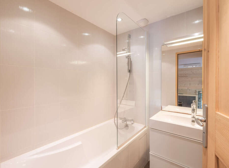 This modern bathroom features a sleek design with a bathtub and a glass shower screen.