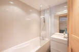 This modern bathroom features a sleek design with a bathtub and a glass shower screen.