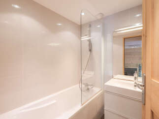 This modern bathroom features a sleek design with a bathtub and a glass shower screen.