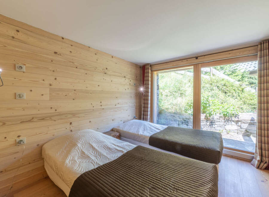 This cozy bedroom features beautiful wooden paneling and two comfortable beds, perfect for a relaxing stay.