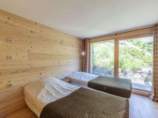 This cozy bedroom features beautiful wooden paneling and two comfortable beds, perfect for a relaxing stay.