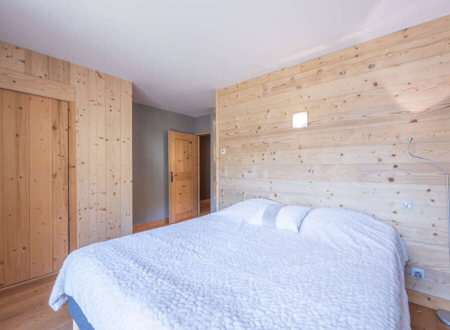 This cozy bedroom features a stunning wooden wall that adds warmth and character to the space.