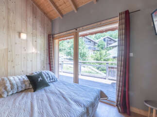 Experience the charm of this cozy bedroom, featuring a stunning view through large windows.