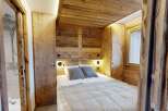 Experience rustic charm in this cozy bedroom, featuring stunning wood paneling and a warm, inviting atmosphere.