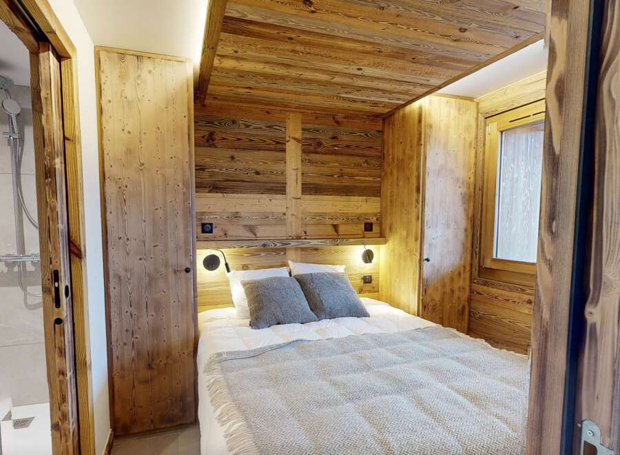 Experience rustic charm in this cozy bedroom, featuring stunning wood paneling and a warm, inviting atmosphere.