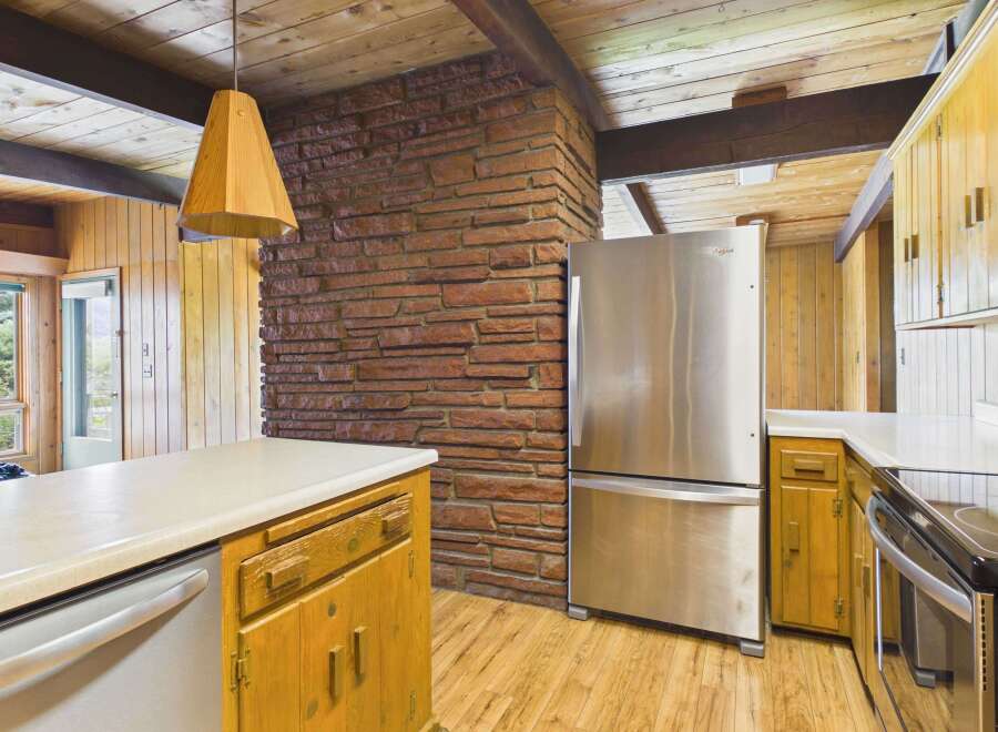 This charming kitchen boasts a rustic aesthetic with its exposed brick wall and warm wooden cabinetry.