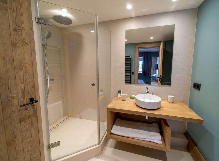 Step into luxury with this stunning bathroom! Featuring a modern design, this space boasts a sleek shower, a stylish sink, and a beautiful wooden door.