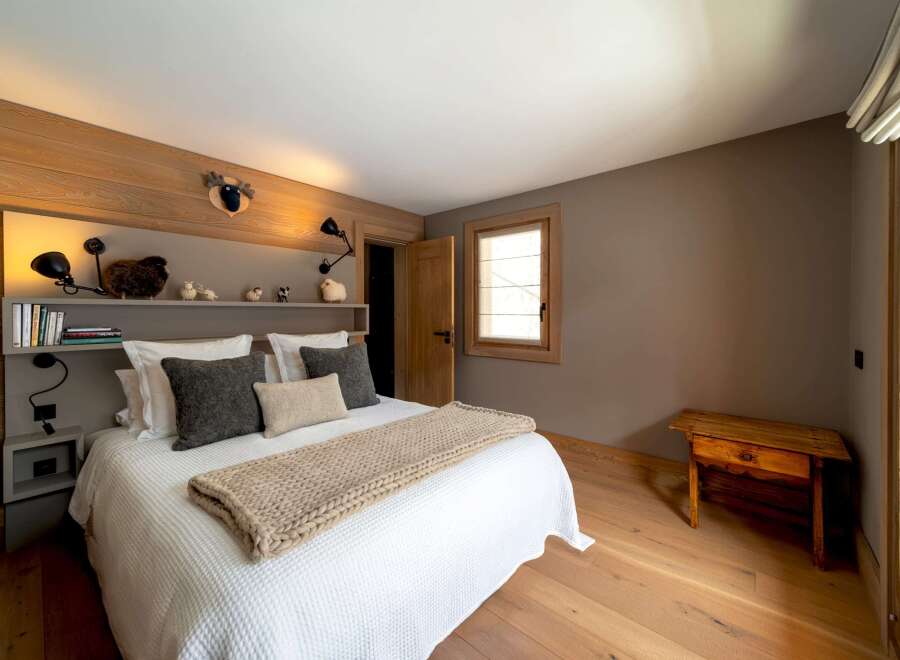 This cozy bedroom features a rustic wooden headboard and flooring, creating a warm and inviting atmosphere.