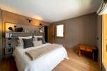 This cozy bedroom features a rustic wooden headboard and flooring, creating a warm and inviting atmosphere.