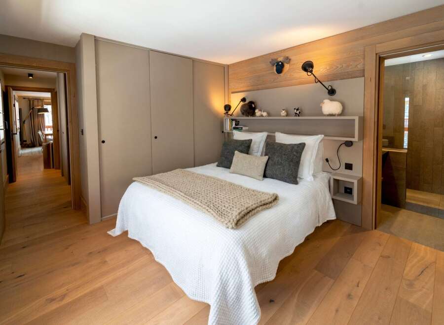 This cozy bedroom features a warm, inviting atmosphere with its wooden floors and neutral color palette.