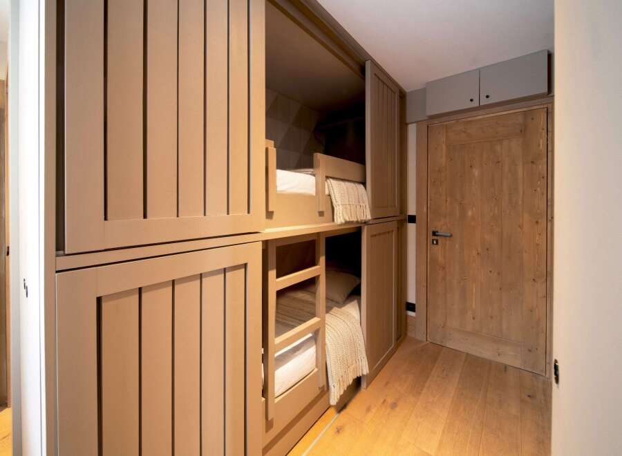 This cozy bunk room features custom-built bunk beds with integrated storage, perfect for maximizing space in a vacation home or rental property.