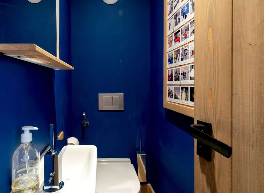 This modern bathroom features a sleek design with a vibrant blue wall and natural wood accents.