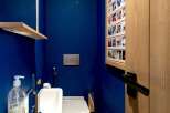 This modern bathroom features a sleek design with a vibrant blue wall and natural wood accents.