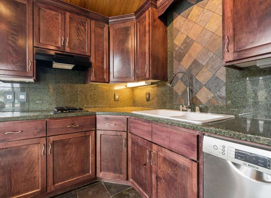 This stunning kitchen boasts rich, dark wood cabinetry and sleek granite countertops, creating a warm and inviting atmosphere.