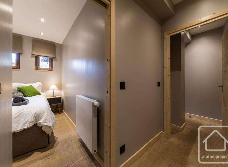 This cozy bedroom features a comfortable bed with fresh linens and a vibrant green pillow, creating a relaxing atmosphere.