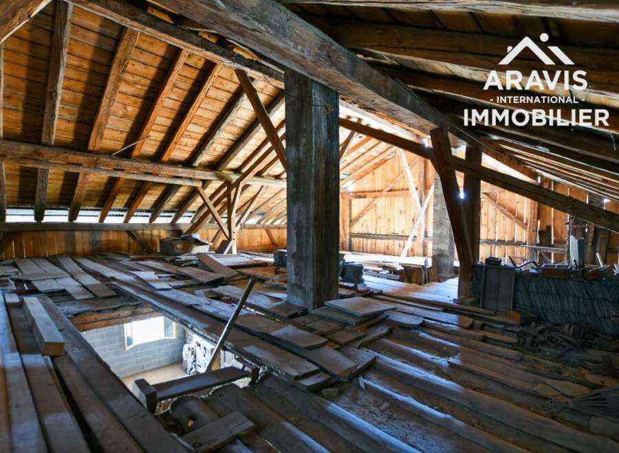 Explore the potential of this unique property! This image showcases a spacious attic with exposed wooden beams, offering a blank canvas for renovation.
