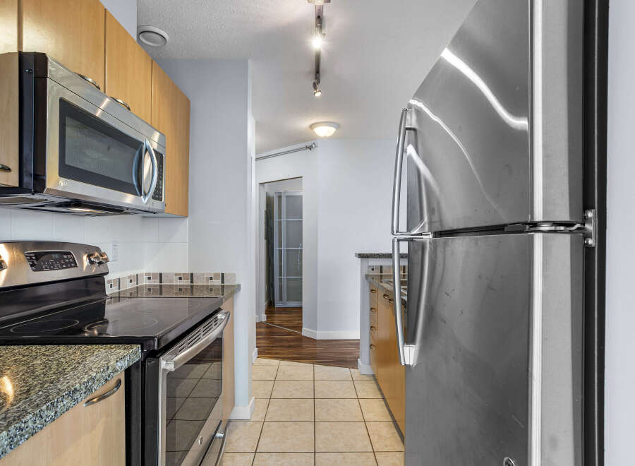 Step into this modern kitchen, featuring sleek stainless steel appliances and ample counter space.