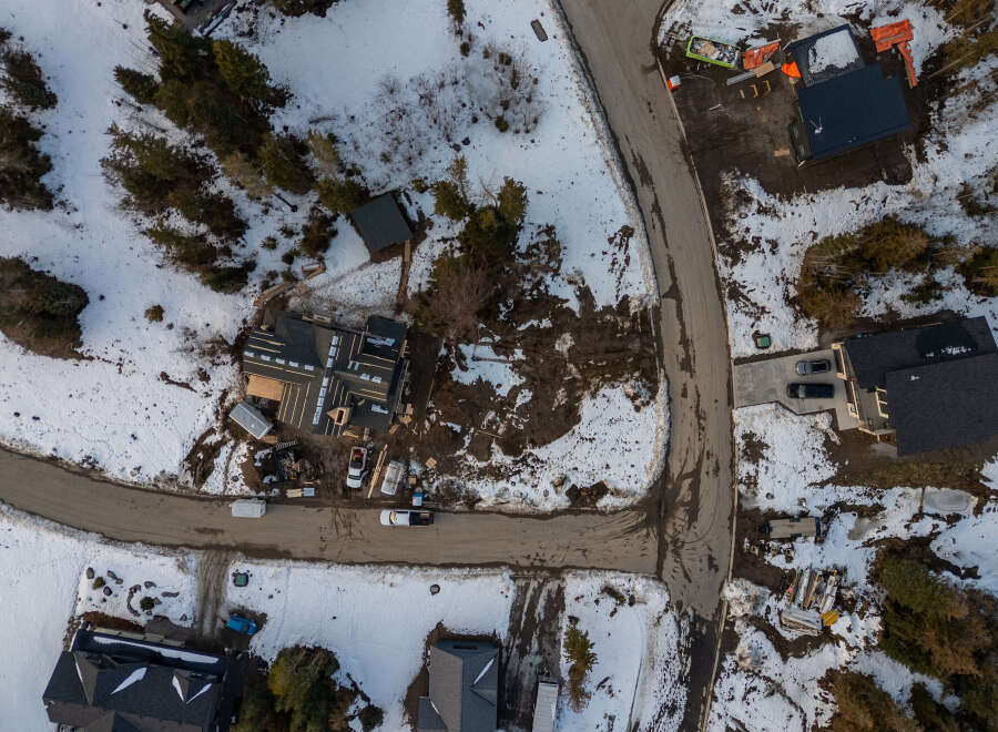 This aerial view showcases a modern home under construction in a serene, snow-covered neighborhood.