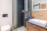 This modern bathroom features a sleek glass shower, a stylish floating sink, and a rustic wooden vanity.