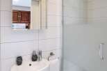 This modern bathroom features a sleek, white design with a glass shower enclosure.