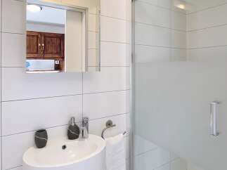This modern bathroom features a sleek, white design with a glass shower enclosure.
