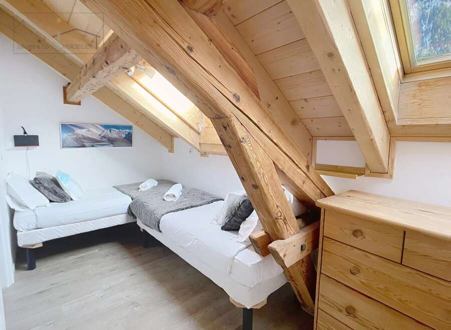 This charming bedroom features a unique architectural design with exposed wooden beams and a slanted ceiling, creating a cozy and inviting atmosphere.