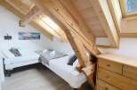 This charming bedroom features a unique architectural design with exposed wooden beams and a slanted ceiling, creating a cozy and inviting atmosphere.