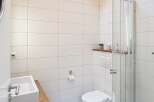 This modern bathroom features a sleek design with white tiles and a glass shower enclosure.