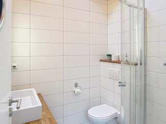 This modern bathroom features a sleek design with white tiles and a glass shower enclosure.