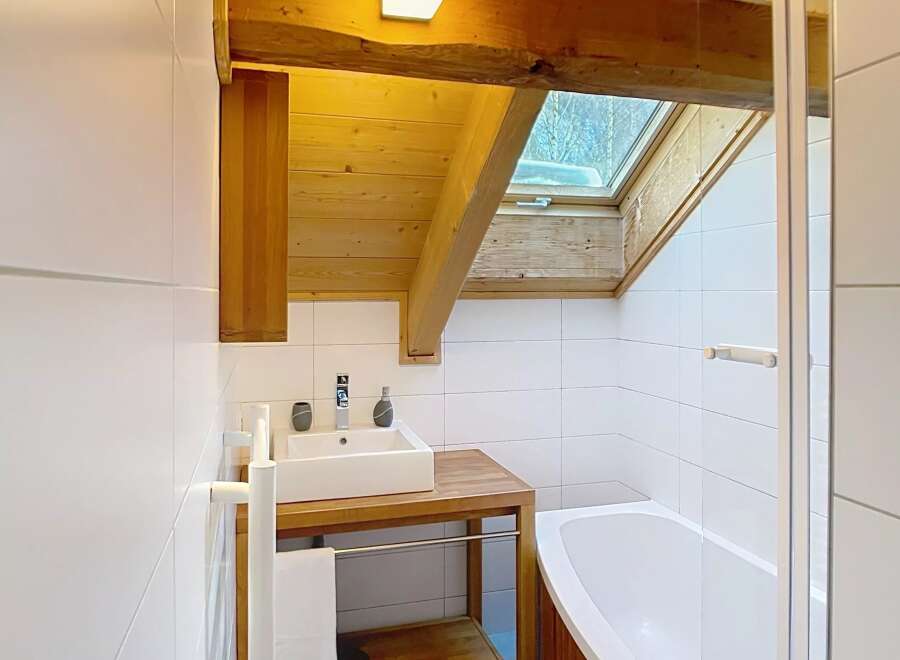 This stunning bathroom boasts a unique design with exposed wooden beams and a skylight, creating a warm and inviting atmosphere.