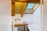 This stunning bathroom boasts a unique design with exposed wooden beams and a skylight, creating a warm and inviting atmosphere.