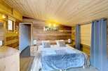 Experience the warmth of this charming bedroom, featuring a cozy wooden interior and a comfortable bed.