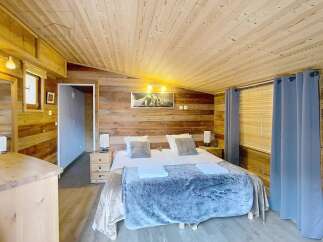 Experience the warmth of this charming bedroom, featuring a cozy wooden interior and a comfortable bed.