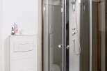 This modern bathroom features a sleek, corner shower with glass doors, offering a spa-like experience.