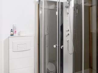 This modern bathroom features a sleek, corner shower with glass doors, offering a spa-like experience.