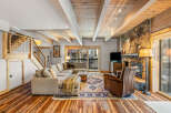 This stunning living room boasts a cozy ambiance with its stone fireplace and exposed wooden beams.