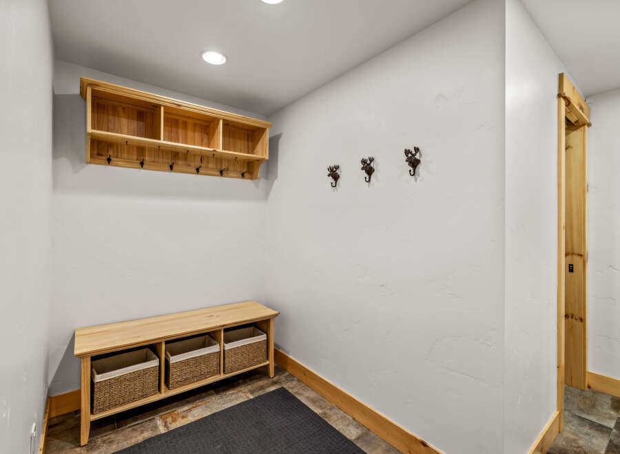 This entryway features a custom-built wooden bench with woven baskets, perfect for storing shoes and accessories.