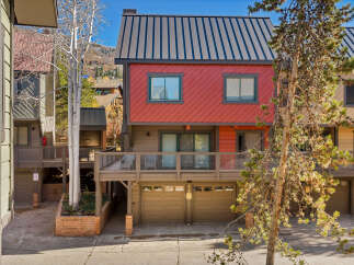 Discover this charming multi-level townhouse featuring a vibrant red facade and a sleek metal roof.