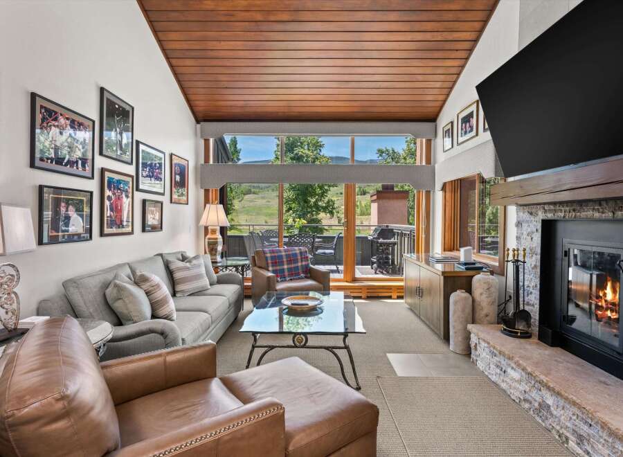 Experience luxurious living in this stunning mountain retreat, featuring a spacious living area with a cozy fireplace and a large window offering breathtaking views.