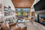 Experience luxurious living in this stunning mountain retreat, featuring a spacious living area with a cozy fireplace and a large window offering breathtaking views.