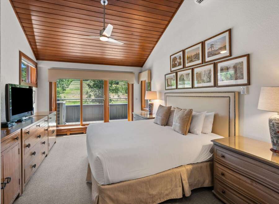 Experience ultimate comfort in this beautifully appointed bedroom, featuring a plush king-sized bed and a charming wooden ceiling with a modern fan.