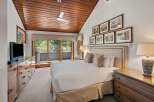 Experience ultimate comfort in this beautifully appointed bedroom, featuring a plush king-sized bed and a charming wooden ceiling with a modern fan.
