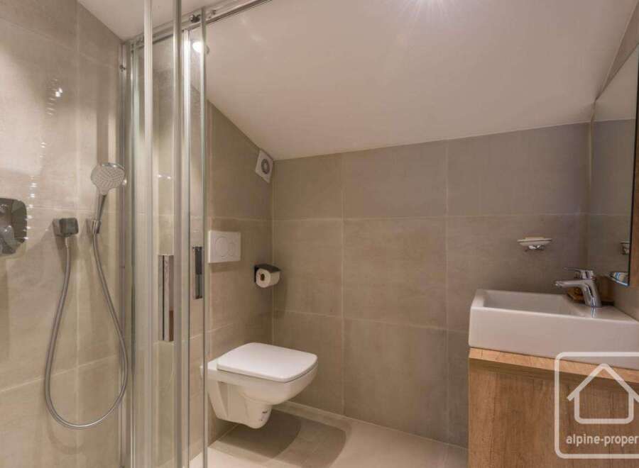 This modern bathroom features a sleek shower, a wall-mounted toilet, and a stylish vanity.