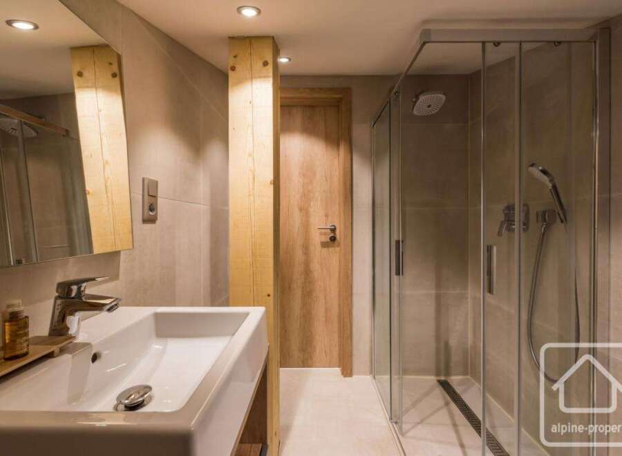 This modern bathroom features a sleek design with a spacious walk-in shower and a stylish sink.