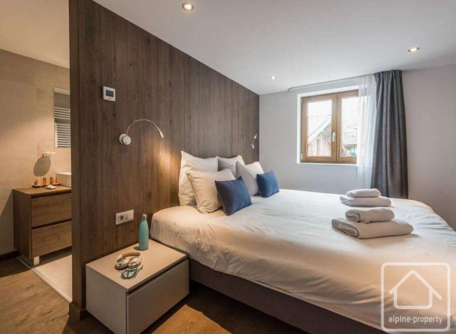 This stunning bedroom boasts a modern design with a wooden accent wall, creating a warm and inviting atmosphere.